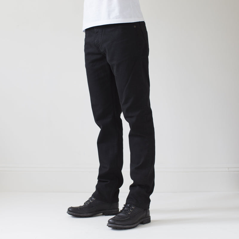 angle: black  A model wears Raleigh Denim Workshop Alexander work fit stretch pants in black, side