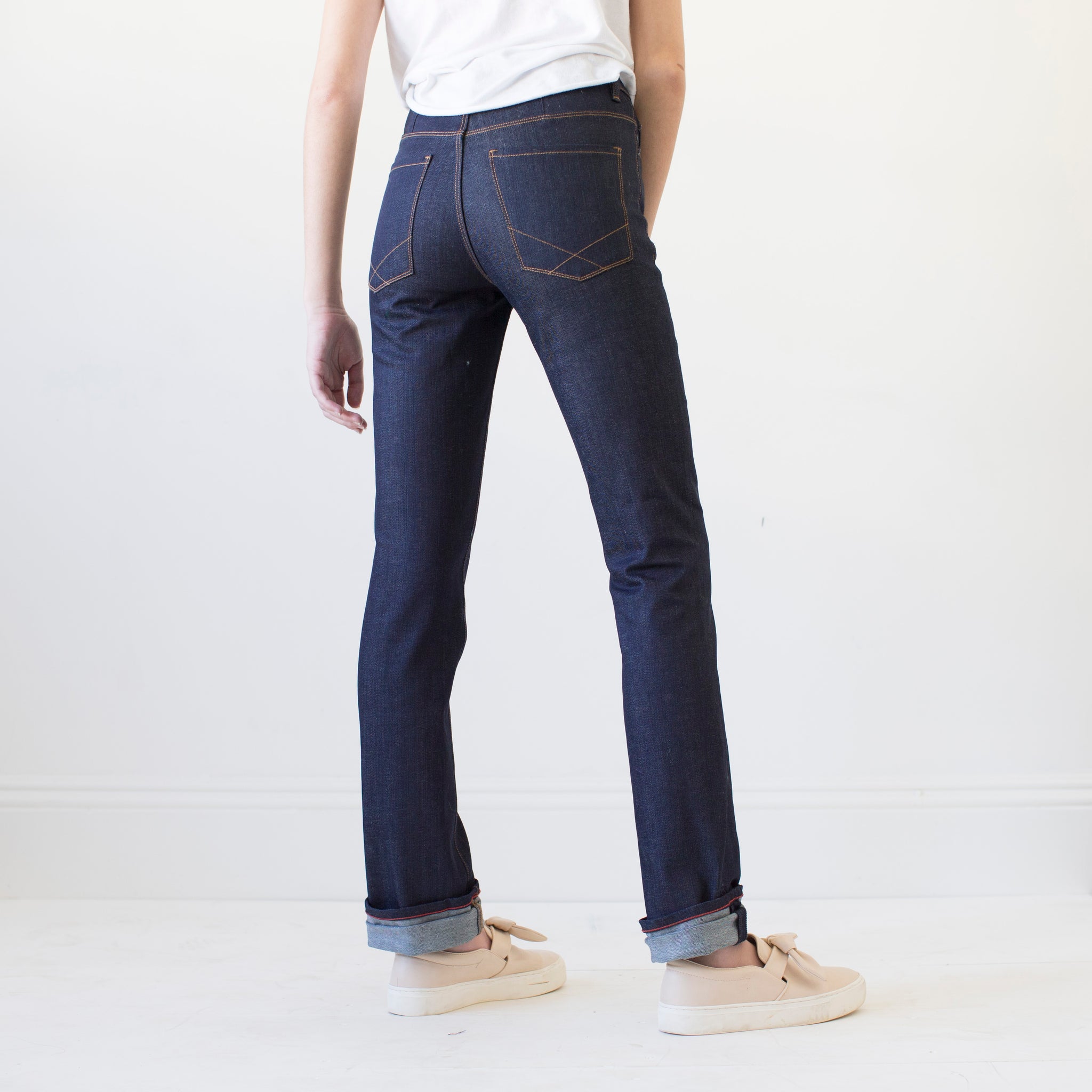 angle: indigo  A model wears Raleigh Denim Workshop Madison high-rise straight leg raw dark jeans, back view