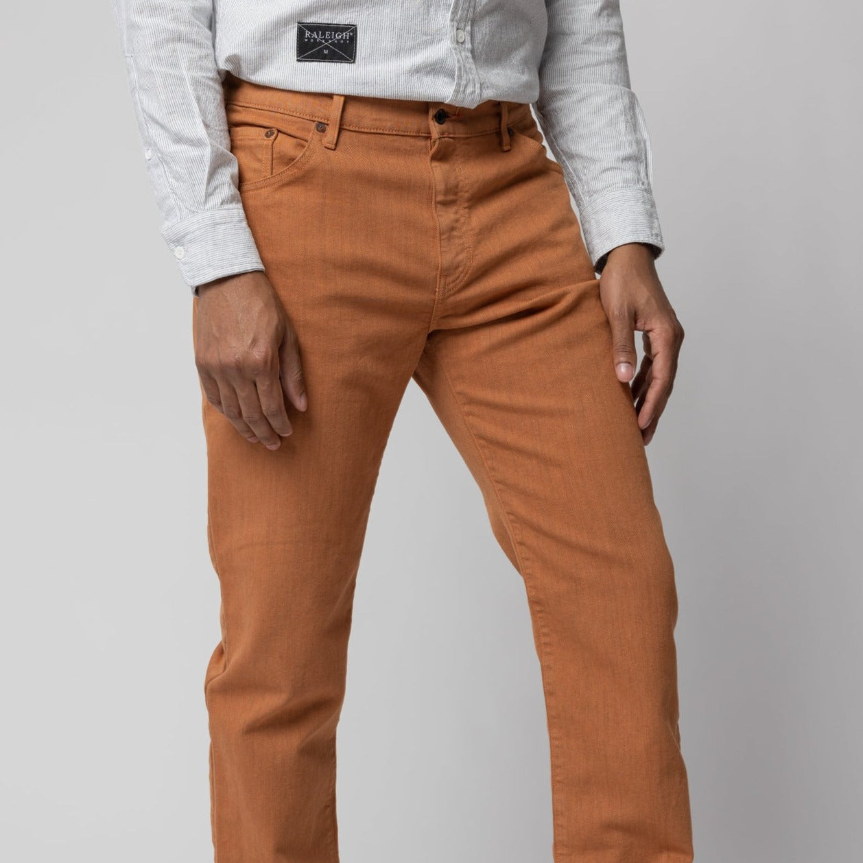 angle hover: Alexander Stretch Terracotta Man wears a Raleigh Workshop denim stretch jean pant in terracotta