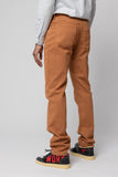 angle: Alexander Stretch Terracotta Man wears a Raleigh Workshop denim stretch jean pant in terracotta