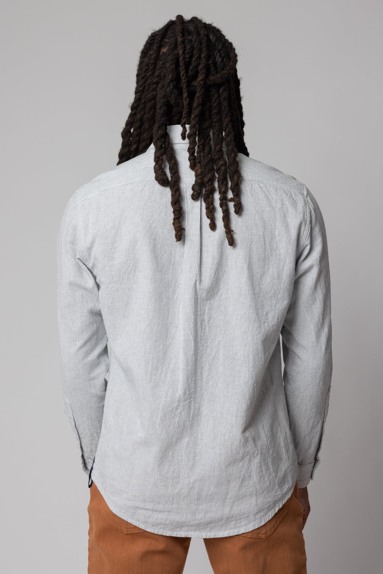 angle: Oxford Ticking Stripe: Man wears white oxford buttonup in ticking stripe